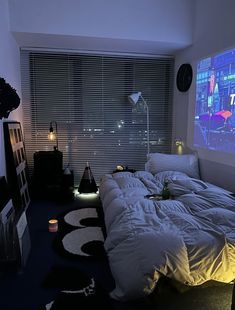 a room with a bed, television and windows that have city lights on the wall