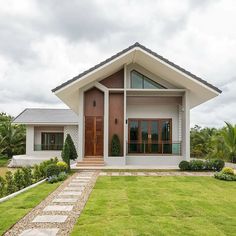 a house that is in the middle of some grass and plants on the side of it