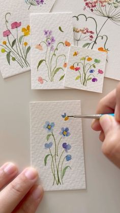 someone is painting flowers with watercolors on paper