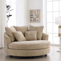 a living room with a round couch and pillows on the floor next to a lamp