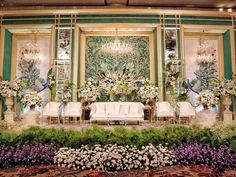 an elaborately decorated stage with flowers and chairs