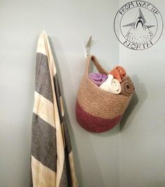 a crochet basket hanging on the wall next to a towel rack with scissors