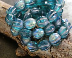 a bunch of blue glass beads sitting on top of a piece of wood next to a tree branch