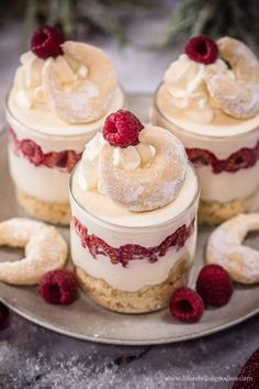 four desserts with raspberries and powdered sugar on a silver platter