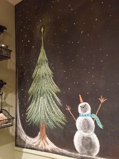 a chalk drawing of a snowman next to a christmas tree