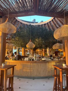 the inside of a restaurant with wooden tables and stools in front of an outdoor bar