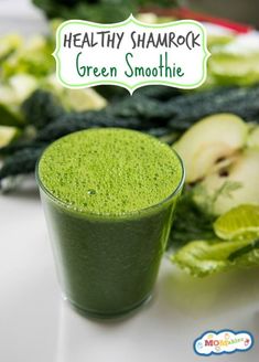 a green smoothie in a glass next to some vegetables