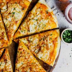 a pizza cut into eight slices on top of a wooden cutting board with sauces and condiments