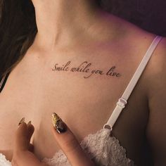 a woman with a tattoo on her chest saying smile while you live next to her