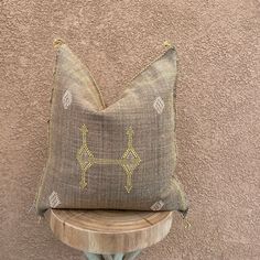 a pillow sitting on top of a wooden table next to a wall with a brown and yellow pattern