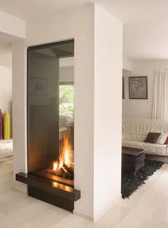 a fire place in the middle of a living room with white walls and flooring