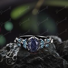 a blue diamond ring sitting on top of a rock