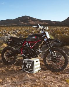 a motorcycle parked on top of a dirt field next to a sign that says graham