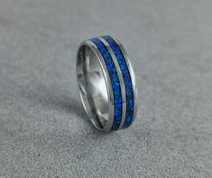 -Mineral(s): Lapis Lazuli -Opal(s): Blue Opal -Ring Material: Stainless Steel 316L -Ring Width: 6mm, 8mm -Shipping: EU:6-10 Workdays, Outside The EU: 7- 14 Workdays -Ring Inside: Comfort Fit Uncover the captivating charm of this stainless steel ring, delicately designed with an inlay featuring crushed lapis lazuli mineral and blue opal. Handcrafted with meticulous attention to detail, this remarkable piece carries profound symbolic meanings, adding depth and beauty to your jewelry collection. Lapis lazuli, known as the stone of wisdom and truth, holds a rich symbolism. Its deep blue hues represent inner peace and spiritual enlightenment. Lapis lazuli is believed to enhance communication and stimulate intellectual abilities, fostering a sense of clarity and self-expression. Let this stone g How To Wear Rings, Blue Opal Ring, Lapis Lazuli Ring, Unique Wedding Gifts, Stainless Steel Ring, Ring Blue, Ring Black, Ring Promise, Opal Ring