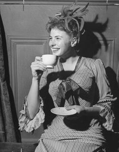 a woman sitting down holding a cup and saucer