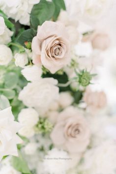 white flowers and greenery are arranged in a vase