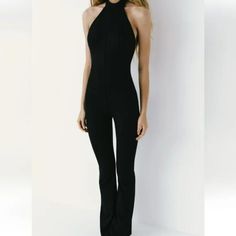 Full Length Jumpsuit Made Of Technical Fabric. Halter Neckline And Open Back. Button Closure At Neck And Hidden In Seam Zipper At Back Chic Stretch One-piece Jumpsuits And Rompers, Chic Stretch Jumpsuits And Rompers, Fitted Black Overall Jumpsuits And Rompers, Chic Fitted High Waist Jumpsuits And Rompers, Fitted Black Overall Jumpsuit, Black Fitted Overall Jumpsuit, Fitted Black Summer Pantsuit, Fitted Black Pantsuit For Summer, Black Fitted Summer Pantsuit