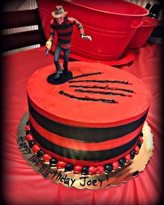 a red and black birthday cake with a figure on top