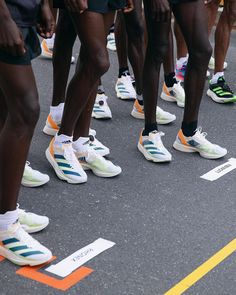 a group of people standing next to each other on top of a street with tennis shoes