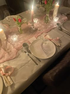 the table is set with plates, silverware and pink napkins for an elegant dinner