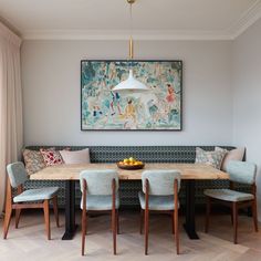 a dining room table with four chairs and a painting on the wall in the background