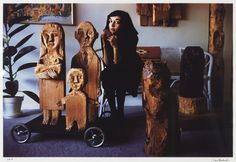 a woman standing next to some carved wooden figures