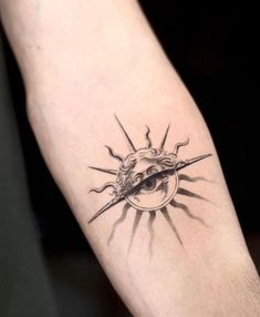 a black and white photo of a sun tattoo on the arm