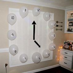 a clock made out of balloons on the wall in a room with white cabinets and lights