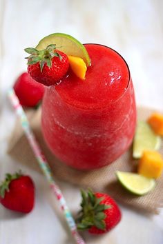 a red drink with strawberries and kiwi on the side