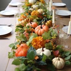 a long table is decorated with pumpkins and greenery