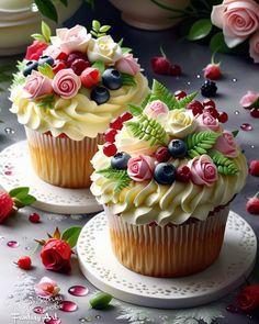 two cupcakes decorated with flowers and berries