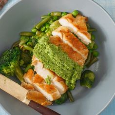 a bowl filled with meat and vegetables on top of a blue table next to a wooden spatula