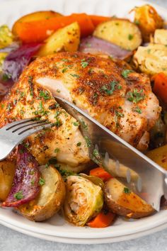 a white plate topped with chicken, potatoes and veggies next to a fork