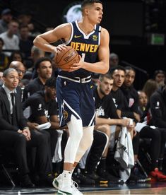 a basketball player dribbling the ball while standing in front of an audience at a game