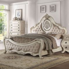 a white bed sitting in a bedroom next to a dresser and mirror on top of a rug