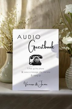 there is a sign that says audio guestbook on the table next to vases with flowers