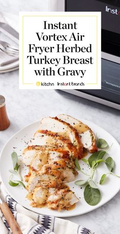 a white plate topped with chicken covered in gravy next to a toaster oven