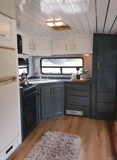 a kitchen area with wooden floors and white cabinets in an rv or camper trailer