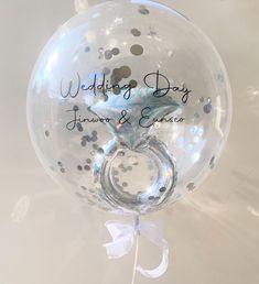 a clear bubble balloon with a silver ring on it's side and the words wedding day