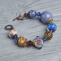 "This Lavender boho bracelet bracelet is a perfect gift for women. It's very tender and unique! This lampwork bracelet fits a 15.5-16.5cm (6.1\"-6.5\" inch) diameter wrist. If you need bigger or smaller size bracelet, please, write me the diameter of your wrist when making an order. Dimentions: 21cm. Materials: artist lampwork beads, metal and glass beads, metal fittings. Colors used: blue, lavender, lilac. Please, note, each lampwork bead is made by hand and may differ slightly. All the photos Bohemian Crystal Bracelet With Faceted Beads As Gift, Bohemian Czech Glass Beads With Large Beads, Bohemian Czech Glass Large Beads, Bohemian Beaded Bracelets With Faceted Beads For Jewelry Making, Bohemian Crystal Bracelet With Large Beads For Gift, Bohemian Czech Glass Beaded Bracelets With Colorful Beads, Bohemian Beaded Bracelets With Czech Glass, Bohemian Beaded Bracelets With Colorful Czech Glass Beads, Artisan Beaded Glass Bracelets