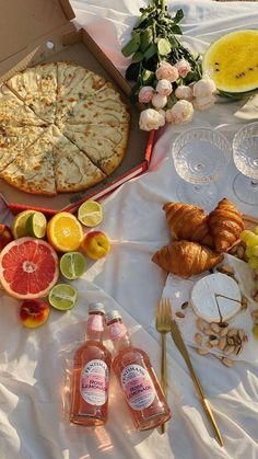 an assortment of food is laid out on a table with wine, fruit and bread