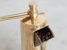 a gold colored coffee grinder with some black berries in the bottom and on top