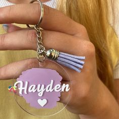 a person holding a keychain with the name hayden on it in front of their face