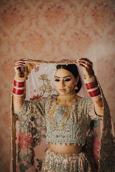 a woman in a bridal outfit holding up a piece of cloth over her head