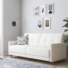 a living room with white furniture and pictures on the wall