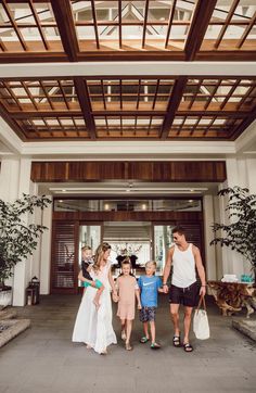 a man and two children are holding hands as they walk into the lobby of a hotel