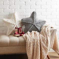 two knitted stars are sitting on a bench next to a blanket and wrapped presents