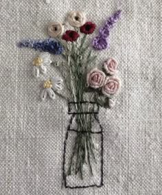 a vase filled with flowers sitting on top of a white cloth covered table next to a wall