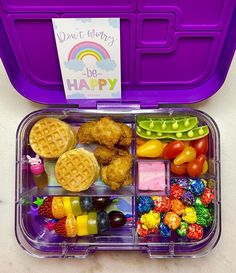 a plastic container filled with different types of food and candy in front of a sign that says don't worry be happy