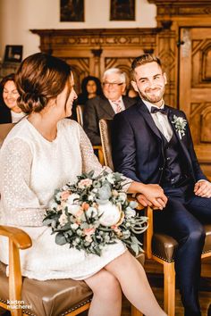 a bride and groom sitting in chairs during a wedding ceremony